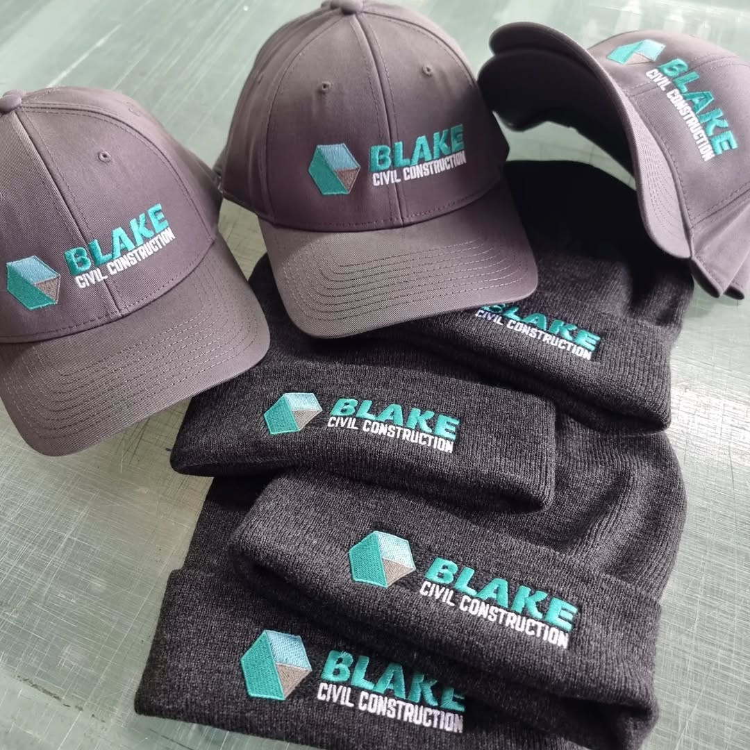 Charcoal caps and beanies with embroidered Blake Civil Construction logo in teal