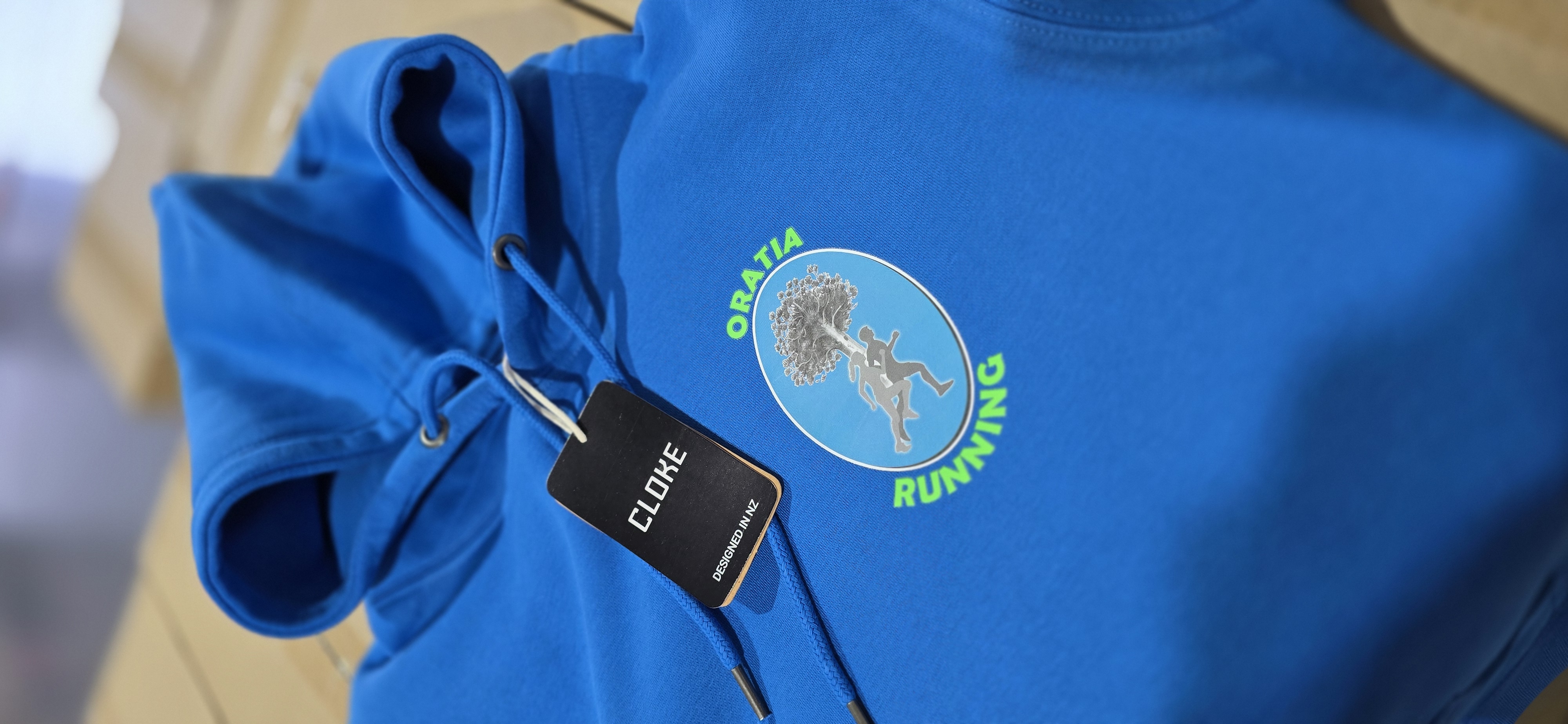 Branded blue Oratia Running hoodie with printed logo for staff