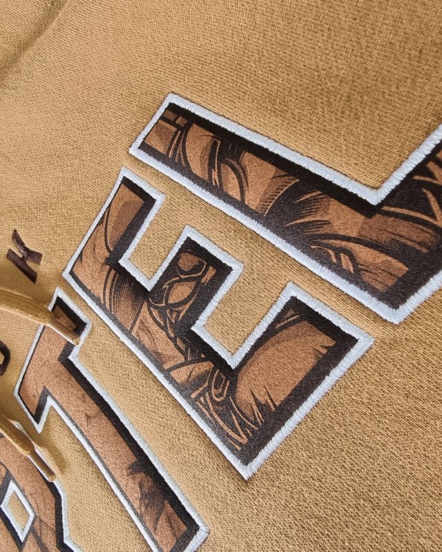 Close-up of embroidered number and monogram detail on Cook Cartel hoodie sleeve